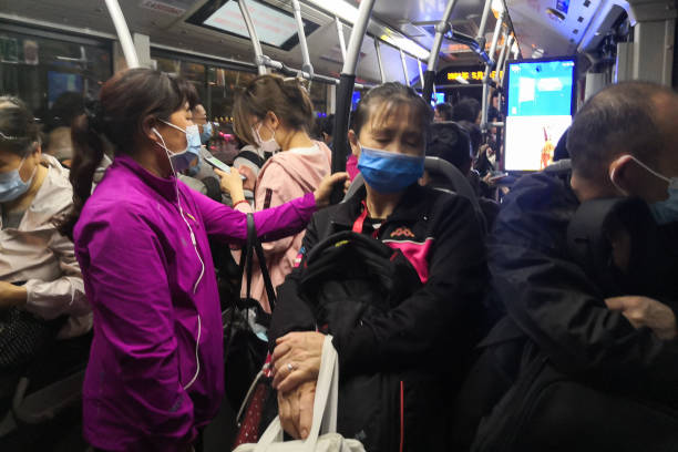 Peopel with masks travel on bus in the evening amid COVID-19 pandemic, Beijing, China. stock photo