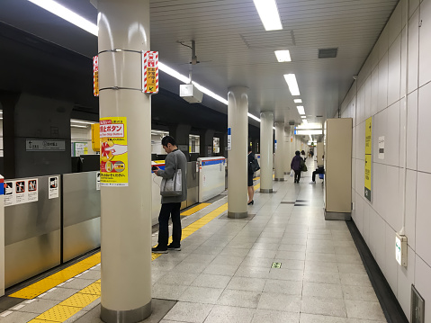 Tokyo, Japan - April 3, 2018: People are waiting for the train to arrive in the Japanese subway. Passengers are in order when boarding and stand to the side of the exit.