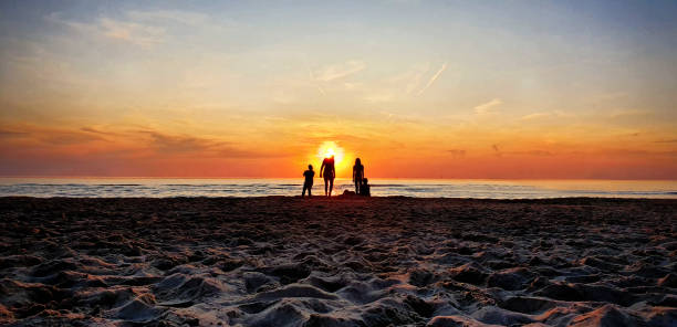 mensen op het strand tijdens golden sunset - nederland strand stockfoto's en -beelden