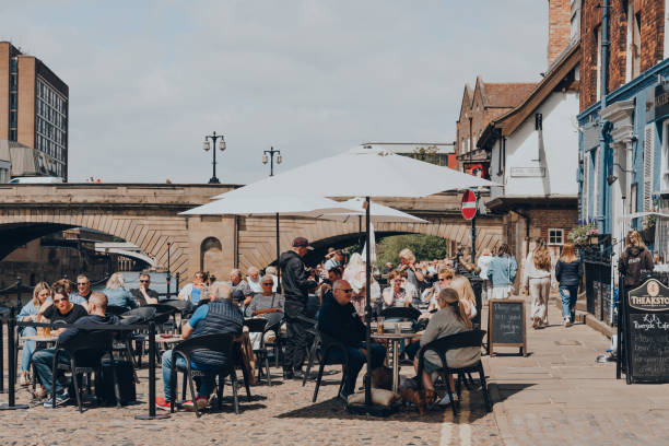 People at the outdoor tables of a pub on the bank of the River Ouse in York, UK. stock photo