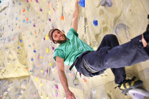 people bouldering in a climbing hall - indoor sports people bouldering in a climbing hall - indoor sports bouldering stock pictures, royalty-free photos & images