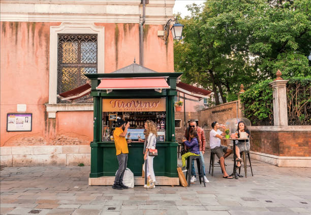 People drinking wine near a street food kiosk with snacks and Aperol cocktails in historical area stock photo