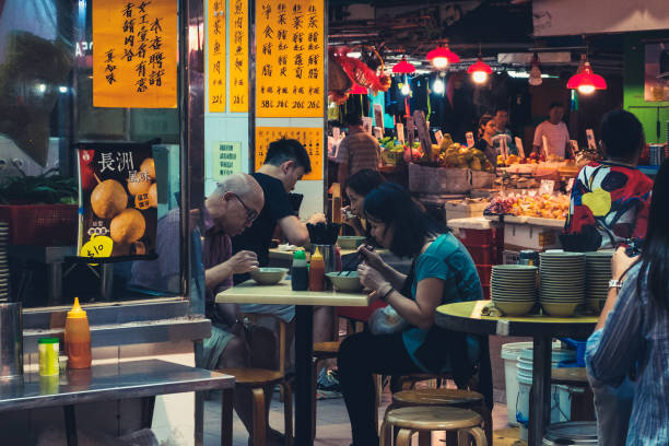 People eating in outdoor street food restaurant in Hong Kong at night stock photo