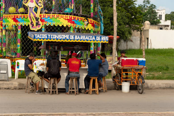 gente comiendo tacos en un puesto de comida mexicana colorido. - comida callejeras fotografías e imágenes de stock