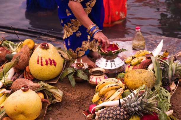 people gathered at river bed and offering fruit and vegetable to sun god people gathered at river bed and offering fruit and vegetable to sun god chhath stock pictures, royalty-free photos & images