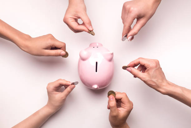 People hands throwing coins in piggy bank for crowdfunding Togetherness concept. People hands throwing coins in piggy bank for crowdfunding, white background charitable donation stock pictures, royalty-free photos & images