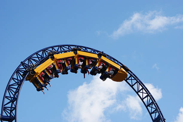 People hanging upside down on the roller coaster track stock photo