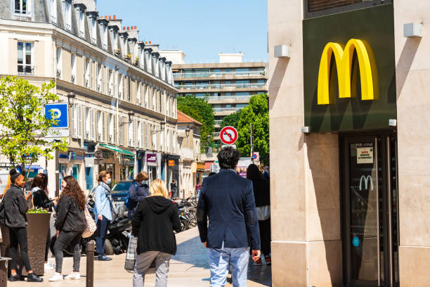 People in masks keep social distance waiting to buy food at McDonald in Parisian suburb. Coronavirus lockdown end, start of deconfinement (easing restrictions). stock photo