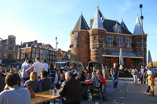 People in outdoor cafe on Nieuwmarkt (New Market) square in center of Amsterdam, Netherlands.The Waag (