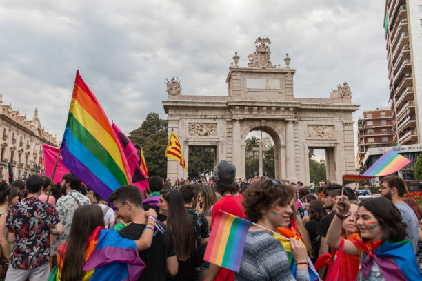 Valencia, Spain - June 16, 2018: People in the gay pride day parade in front of a monument with a big cross stock photo