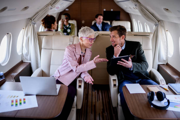 People inside private airplane Group of people traveling by private jet airplane. Couple in front view is having business meeting. private airplane stock pictures, royalty-free photos & images