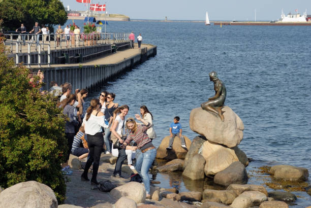 People looking at the Little Mermaid statue in Copenhagen. stock photo