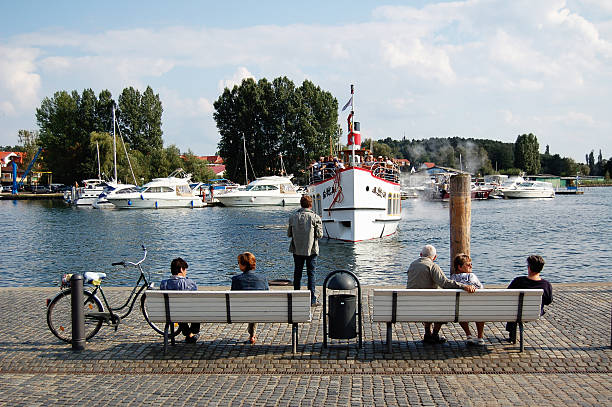 menschen auf der bank sie ein tourist boot im hafen - waren mecklenburg stock-fotos und bilder
