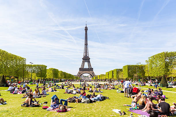 People on Champ de Mars with Eiffel Tower on background Paris, France - May 5, 2016: Lots of people relaxing and having fun on Champ de Mars with the Eiffel Tower on background on a sunny day. champ de mars photos stock pictures, royalty-free photos & images