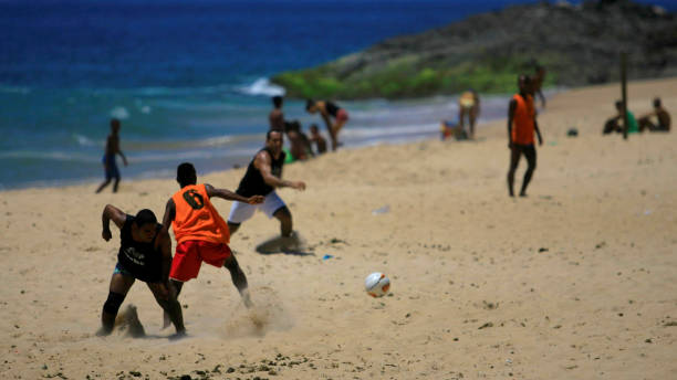 people playing football on the beach in salvador - futebol de praia imagens e fotografias de stock