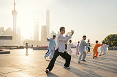 Shanghai, China - October 28, 2015: People practice tai chi in the Bund area as the Oriental Pearl Tower and other commercial buildings stand in the Lujiazui district.
