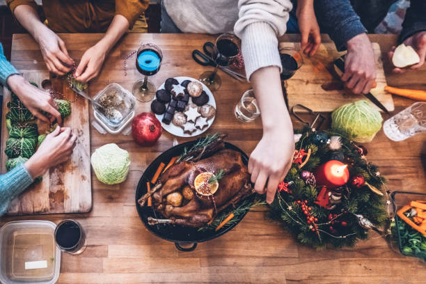 people preparing vegetarian christmas meal and goose roast together on wooden kitchen table stock photo