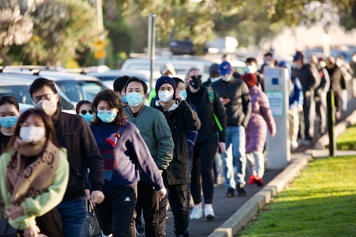 Long queues of people waiting to get coronavirus vaccine at new pop-up walk-in coronavirus vaccination clinic at the Peanut Farm in St Kilda, Melbourne, Victoria, Australia in August 2021 during lockdown. People wear masks but no social distancing, waiting hours in long lines.