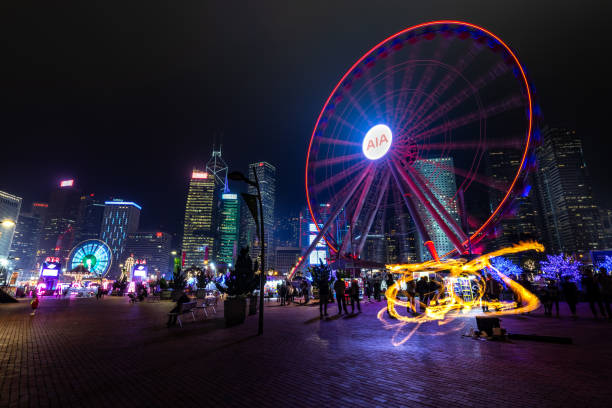 People ride ferris wheel in front of Hong Kong Business District at Night stock photo