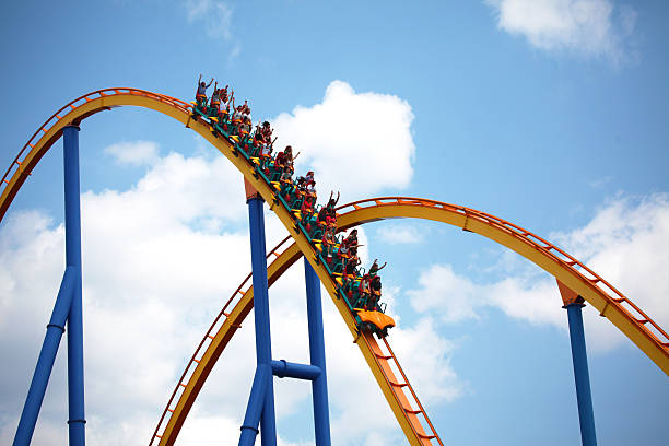 People riding a rollercoaster in an amusement park stock photo
