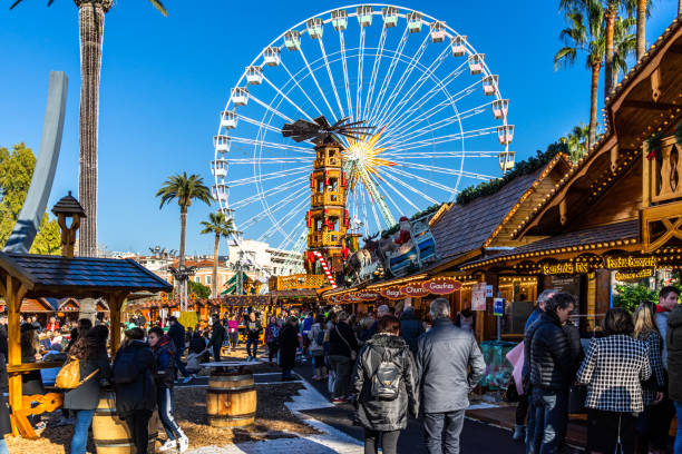 People shopping between the stalls of Nice Christmas market under the Ferris wheel, Nice, France stock photo