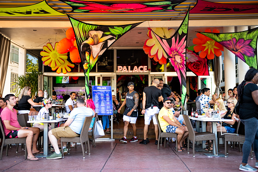 Miami Beach, USA - May 5, 2018: People sitting eating drinking at The Palace bar restaurant in Florida Art Deco district of South Beach on Ocean drive in summer