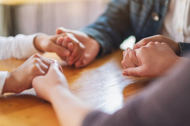 people sitting in a circle holding hands and pray together or in therapy session Group of people sitting in a circle holding hands and pray together or in therapy session drug rehab stock pictures, royalty-free photos & images