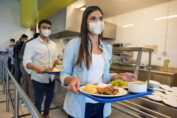 People social distancing and wearing facemasks while having lunch at a buffet Group of Latin American people social distancing and wearing facemasks while having lunch at a buffet -COVID-19 concepts cafeteria stock pictures, royalty-free photos & images