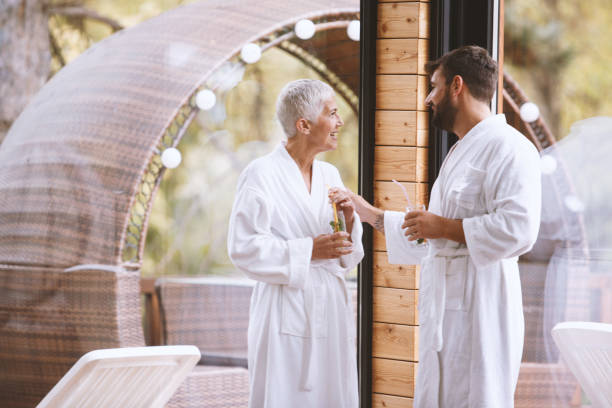 People socialize at the hotel resort Mature woman and young man in bathrobes are talking at the hotel resort. They are having refreshing beverages. cougar woman stock pictures, royalty-free photos & images