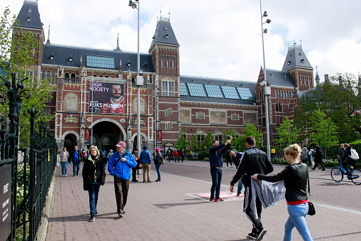 Amsterdam, Netherlands - March 6, 2021: People standing in front of the Rijksmuseum. Due to the rising number of COVID-19 infections, the Netherlands has been in lockdown since 15 December 2020.