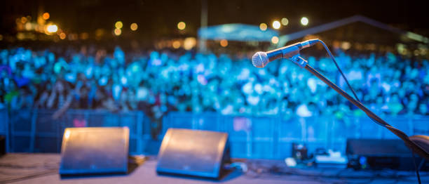 People standing before podium on open-air music festival, focused on microphone stock photo