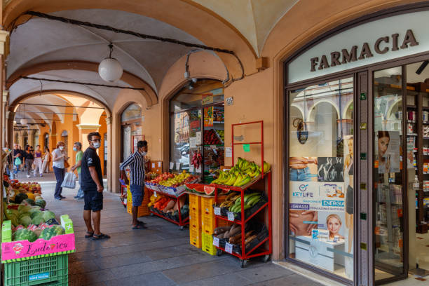 People under an arcade, with a pharmacy and a fruit store (Modena, Italy) stock photo