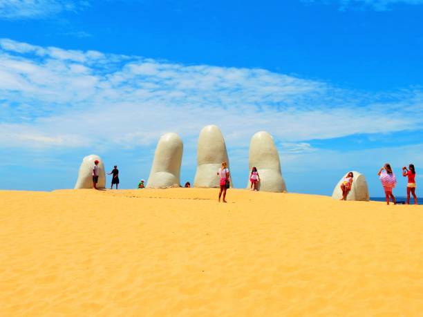 People visiting the sculpture of The Fingers at the Brava Beach in Punta del Este. stock photo