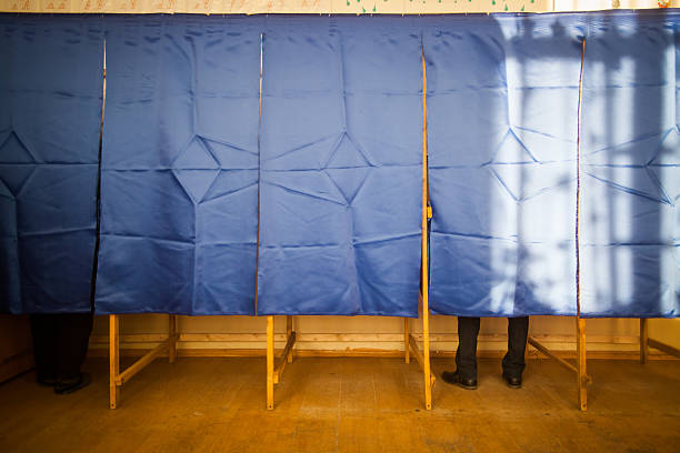 People vote in voting booth People vote in a voting booth at a polling station. voting booth stock pictures, royalty-free photos & images