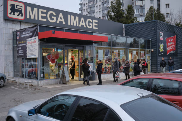 People wait in line in front of a Mega Image supermarket, keeping a safe distance between them, after more strict Coronavirus lockdown measures are announced. stock photo