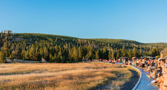 Yellowstone National Park, Wyoming, United States - August 18, 2017: People waiting for the eruption of the cone geyser called Old Faithful. This geyser is part of the Old Faithful Historic District.