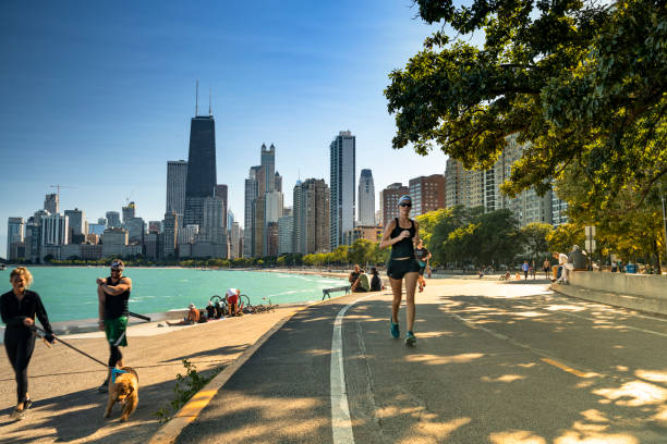 People walk along the Lakefront trail in Chicago Illinois Chicago, Illinois, USA - September 25, 2018:  People walk and exercise along the Lakefront Trail on Lake Michigan and Lake Shore Drive in Chicago, Illinois USA. lakeshore stock pictures, royalty-free photos & images