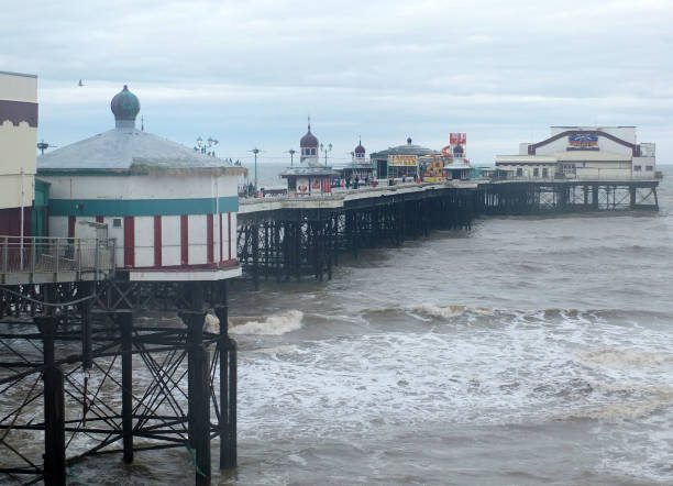 People walking on blackpool north pier on a stormy winter day at high tide Blackpool, Lancashire, England - November 12, 2018: People walking on blackpool north pier on a stormy winter day at high tide north pier stock pictures, royalty-free photos & images
