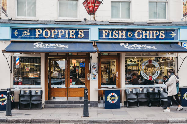 People walking past Poppie's fish and chips shop in Spitalfields, London, UK. stock photo