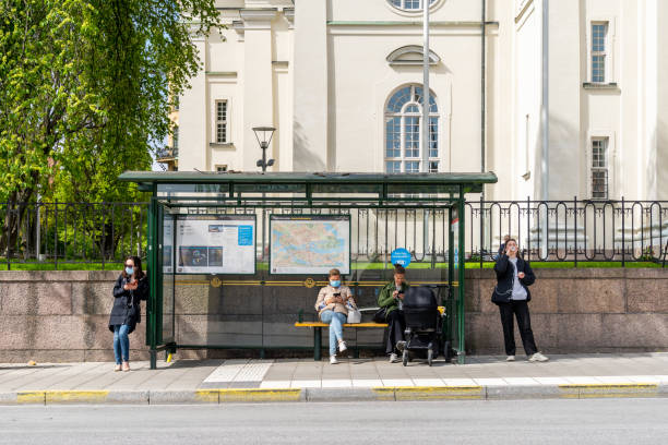 People with face masks waiting at a bus stop. stock photo
