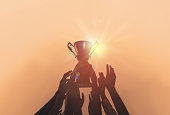 istock People with gold trophy cup on color background, closeup 1338810194