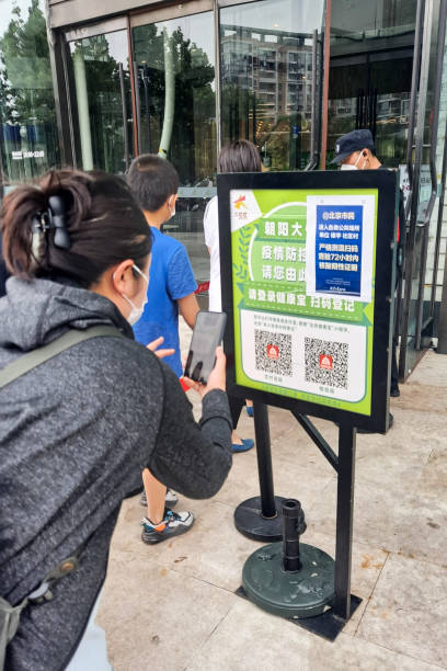 People with masks using mobile phones to scan health QR codes before entering shopping mall amid COVID-19 pandemic. stock photo