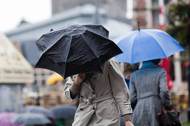 people with umbrellas walking in the city stock photo