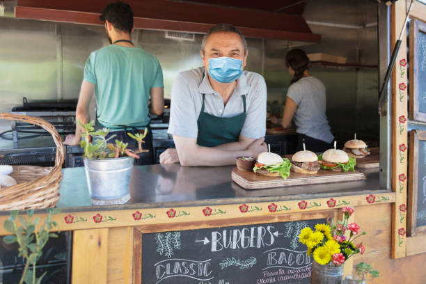 People working in a food truck and wearing protective mask stock photo
