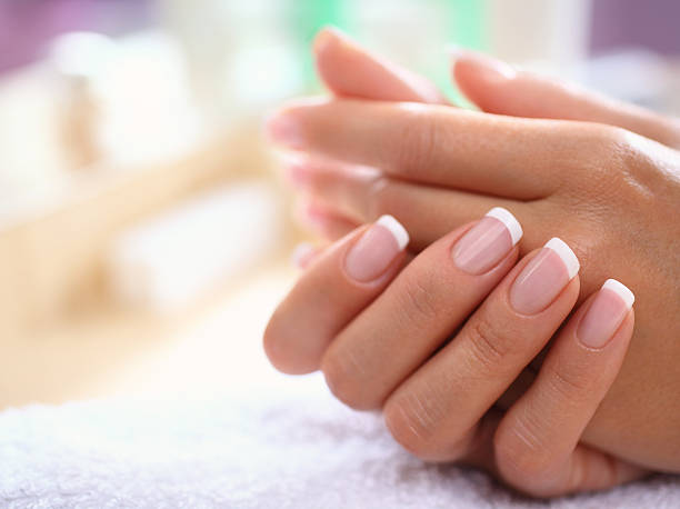 Perfect fingernails. Closeup of fine manicured fingernails on female hands,carefully retouched at 200%. Standard french manicure with transparent nail polish. Hands are placed on white towel. manicure stock pictures, royalty-free photos & images