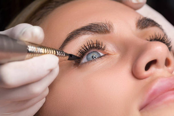 Permanent eye makeup close up shot. Cosmetologist applying tattooing of eyes. Makeup eyeliner procedure stock photo