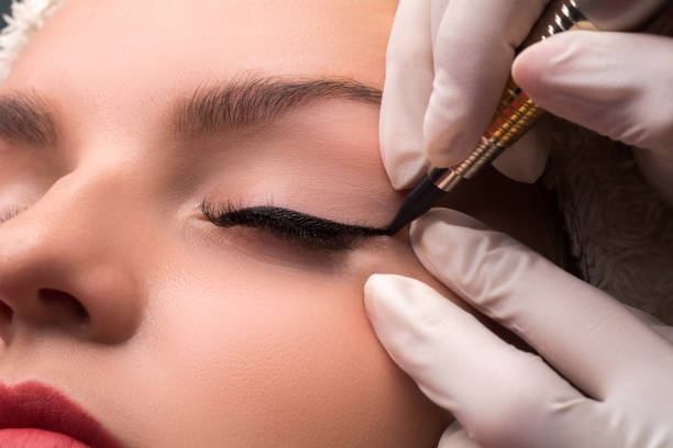Permanent eye makeup close up shot. Cosmetologist applying tattooing of eyes. Makeup eyeliner procedure. stock photo