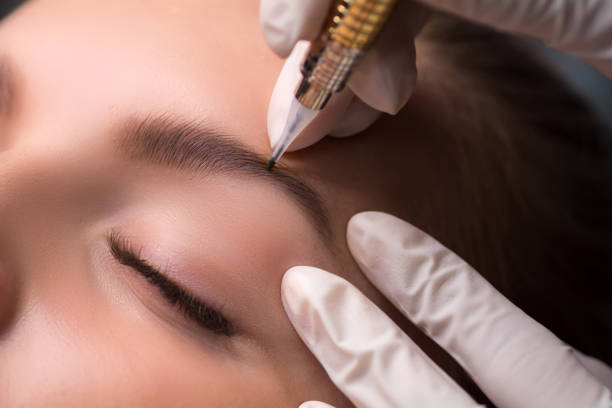 Permanent eyebrow makeup. Cosmetologist applying tattooing of eyebrows. stock photo