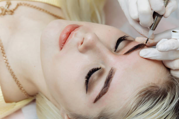 Permanent makeup, tattooing of eyebrows. Cosmetologist applying make up stock photo