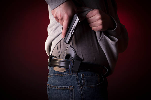A person concealing their pistol on their hip stock photo